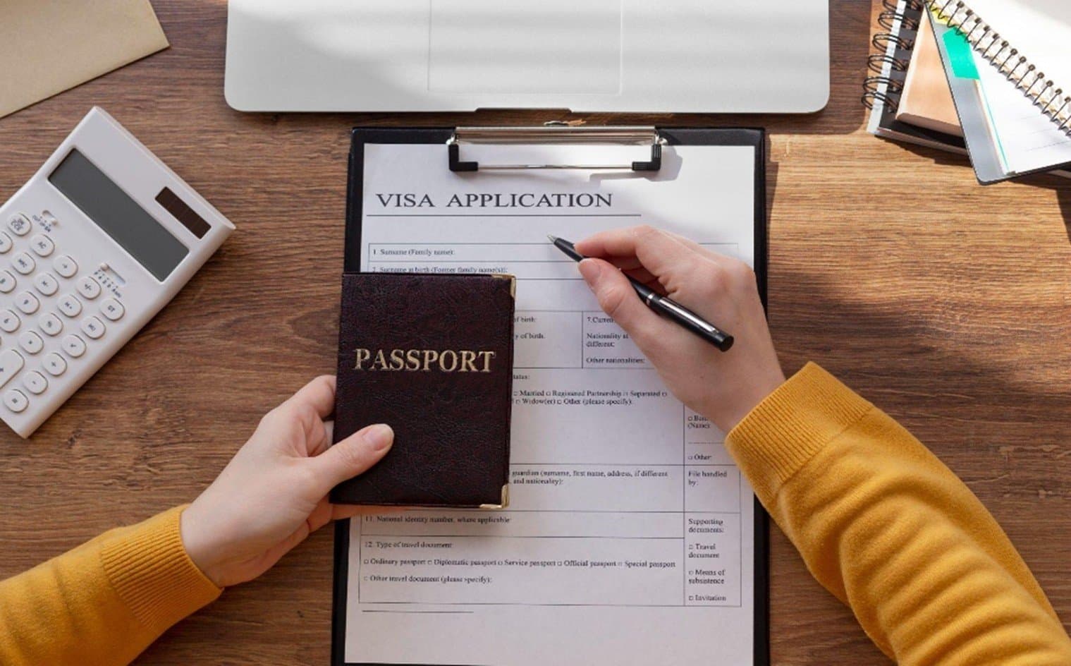 Filling out a visa application form alongside a passport