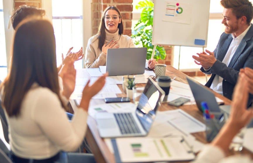 A business team applauding around a meeting table