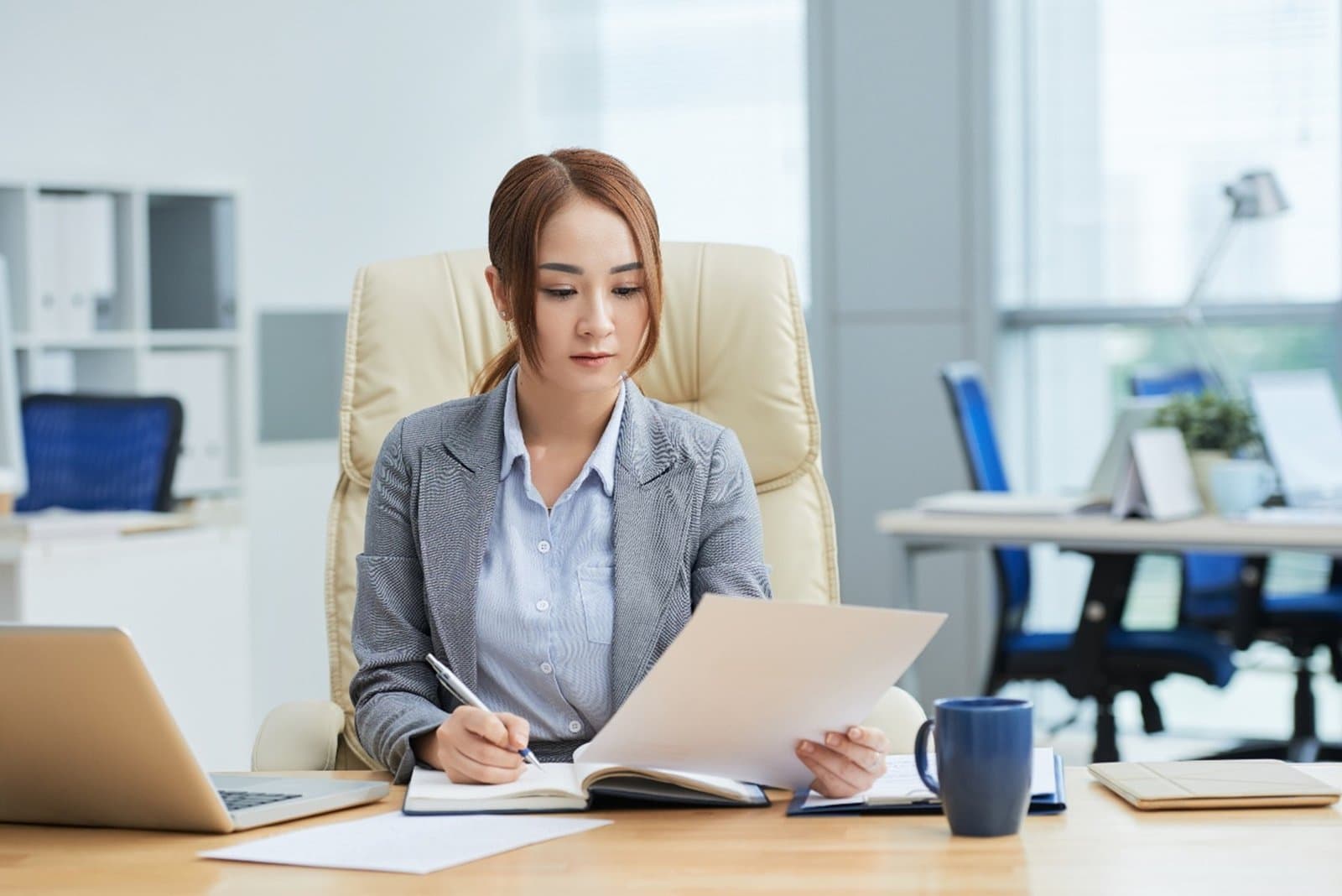 A company director reviewing documents at her desk