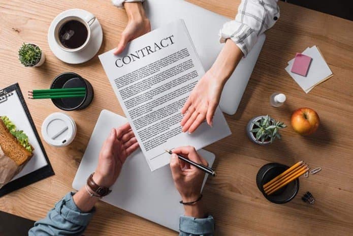 Two people exchanging a signed contract across a desk