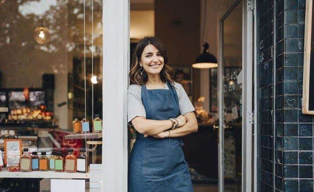 A small business owner standing proudly at the entrance of her shop